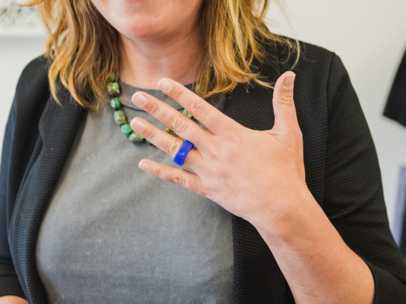 Woman holding up her hand to show off blue resin ring