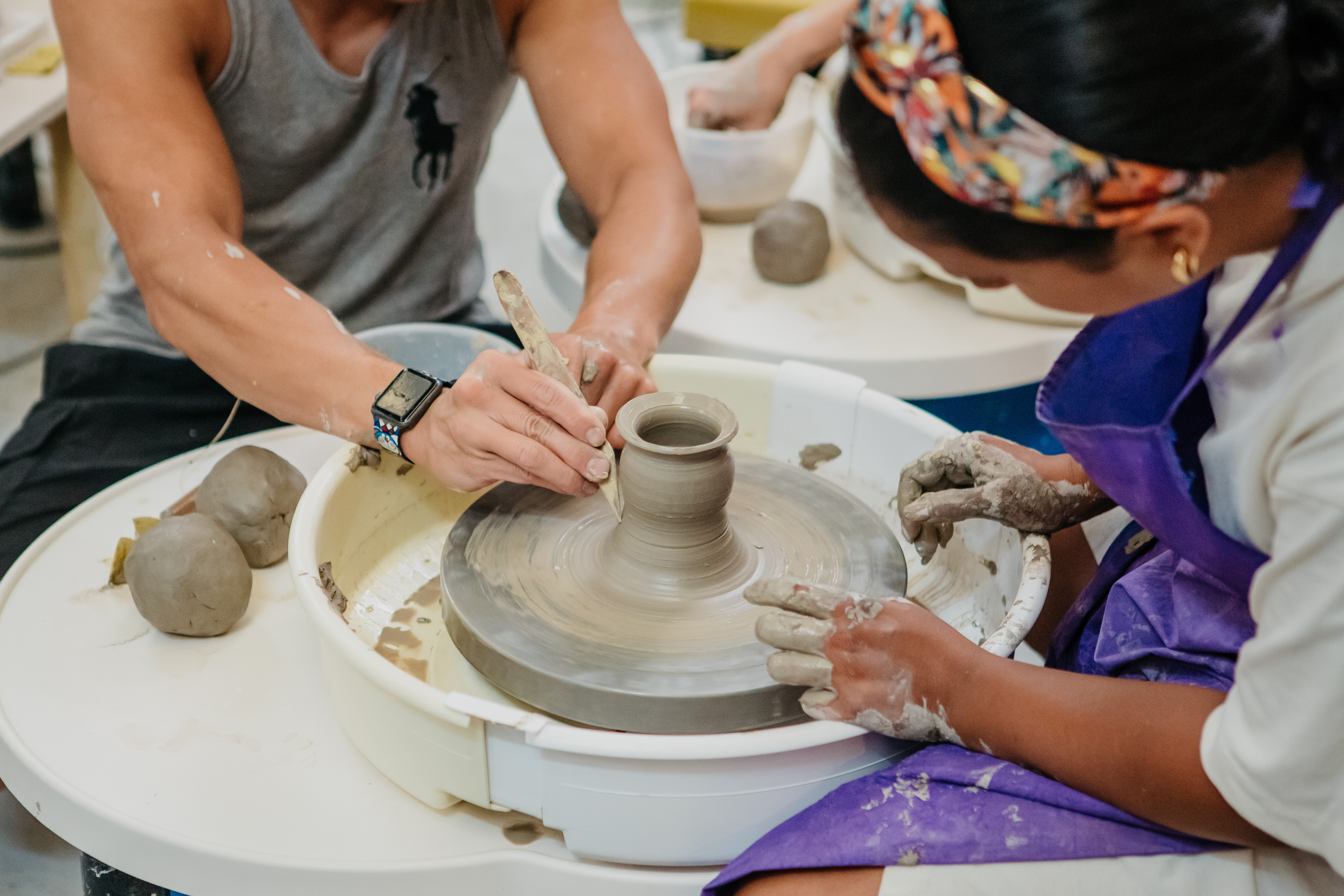 Man and woman working clay on a pottery wheel together